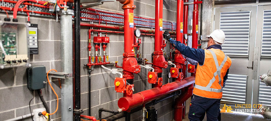 Worker inspecting fire suppression system with red pipes and valves